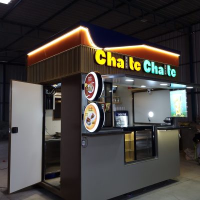 Modern illuminated food kiosk stall named Chalte Chalte inside a warehouse.