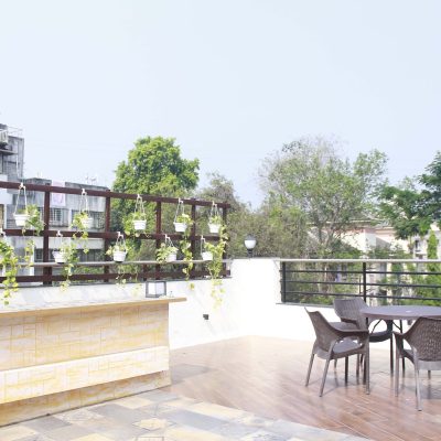 Spacious rooftop terrace with a round dining table, four chairs, and a plant trellis wall.