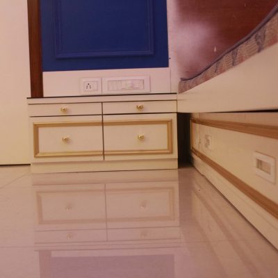 White and gold bedroom nightstand drawers positioned next to a matching platform bed frame with built-in storage.